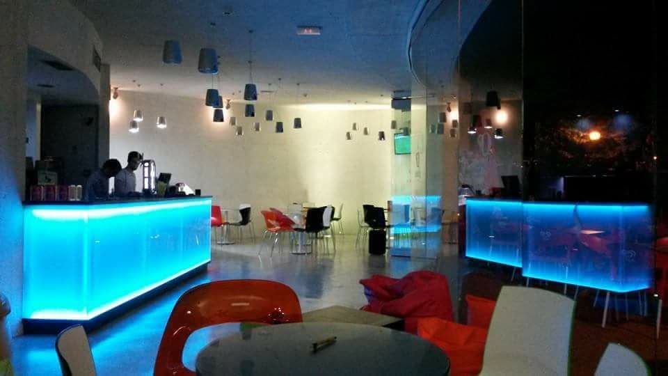 Bar iluminado a azul com pufes vermelhos